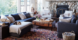 Living room with navy couches, deep rich colored rug, lots of blankets and pillows. 